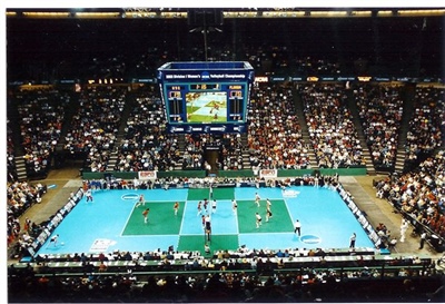 Large indoor arena with a teal and green volleyball court.