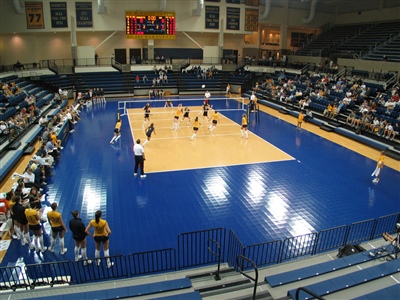 Indoor volleyball court with a beige court and blue floor.