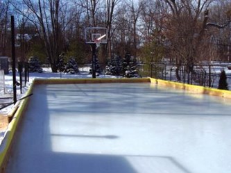 Outdoor ice honkey rink with a small retaining wall and basketball hoop in Mequon.