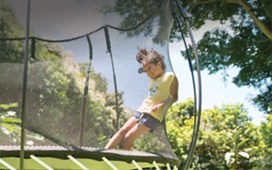 Black trampoline with a black safety net and yellow spring free layer and a child jumping on it in Oconomowoc.