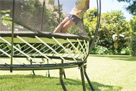 Black trampoline with a yellow spring free layer and a child jumping on it.