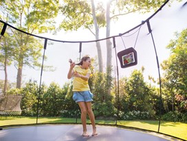 Black trampoline with a black safety net and a child jumping on it. 