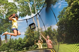 Black trampoline with a black safety net and a child jumping on it. 