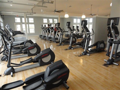 Indoor exercise room with wooden flooring and multiple cardio machines in Mequon.