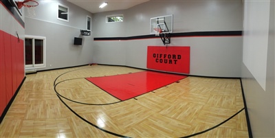  A small indoor basketball court with a polished wood surface, black lines, and grey walls, featuring a red key area in Whitefish Bay.