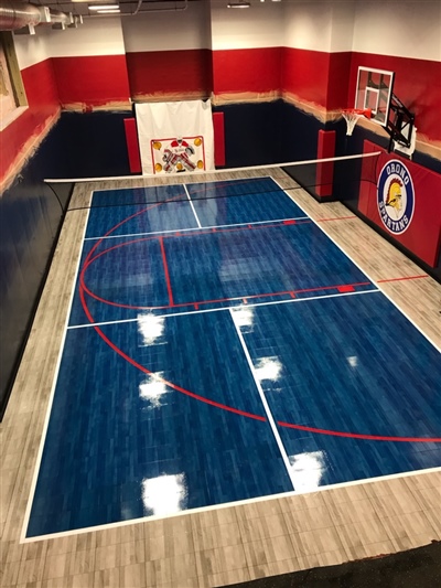 A small indoor basketball court with a blue surface, red lines, and light wood borders in Bayside.