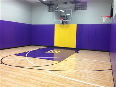 Indoor home basketball court with light wood flooring, purple and yellow wall padding, a purple painted key area, and two basketball hoops in Oconomowoc.