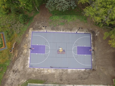 A basketball court with a purple and yellow Vikings-themed surface, featuring white lines and a sport court logo of the Vikings in the center.