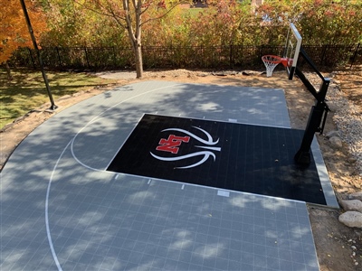 A basketball court with a grey and black surface, white lines, and a sport court logo in the center in Wasuau.