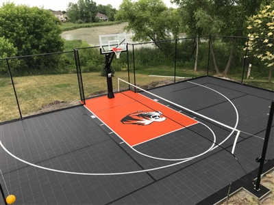 A basketball court with an orange and black surface, white lines, and a sport court logo in the center.