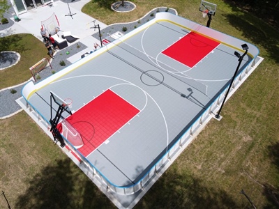 A double sided basketball court with a grey and red surface and white lines with a volleyball net running through it in Eau Claire. 