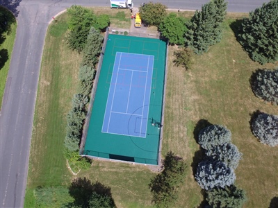 Outdoor sports court with a blue and green surface, featuring basketball hoops and multiple court markings.