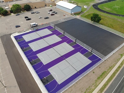 Purple outdoor recreation courts featuring multiple grey basketball and tennis courts.